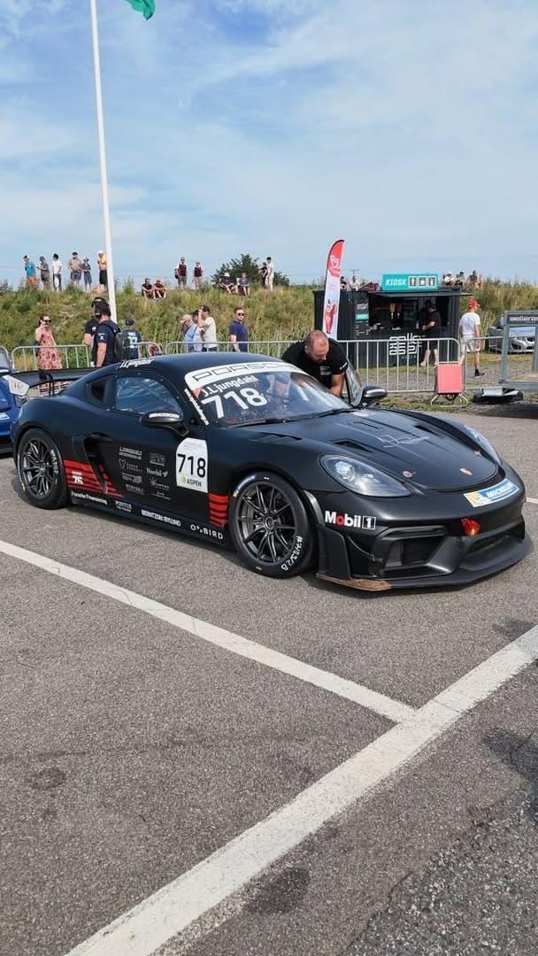 A black Porsche race car, number 718, in the paddock at Gelleråsen